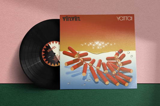 Vinyl record with a colorful cover featuring a shark and red objects on a pink and green gradient background.