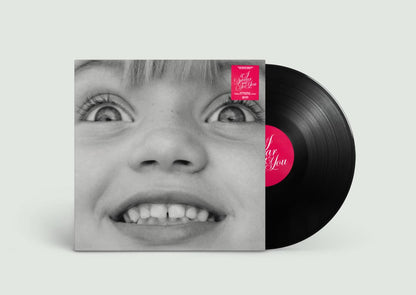 Vinyl record with a cover featuring a close-up of a person's face and a pink label on a light gray background