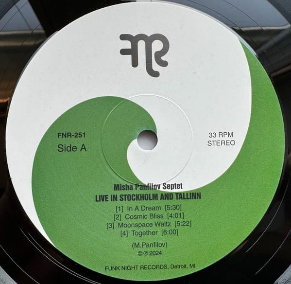 Vinyl record label with green and white design featuring text and a logo.