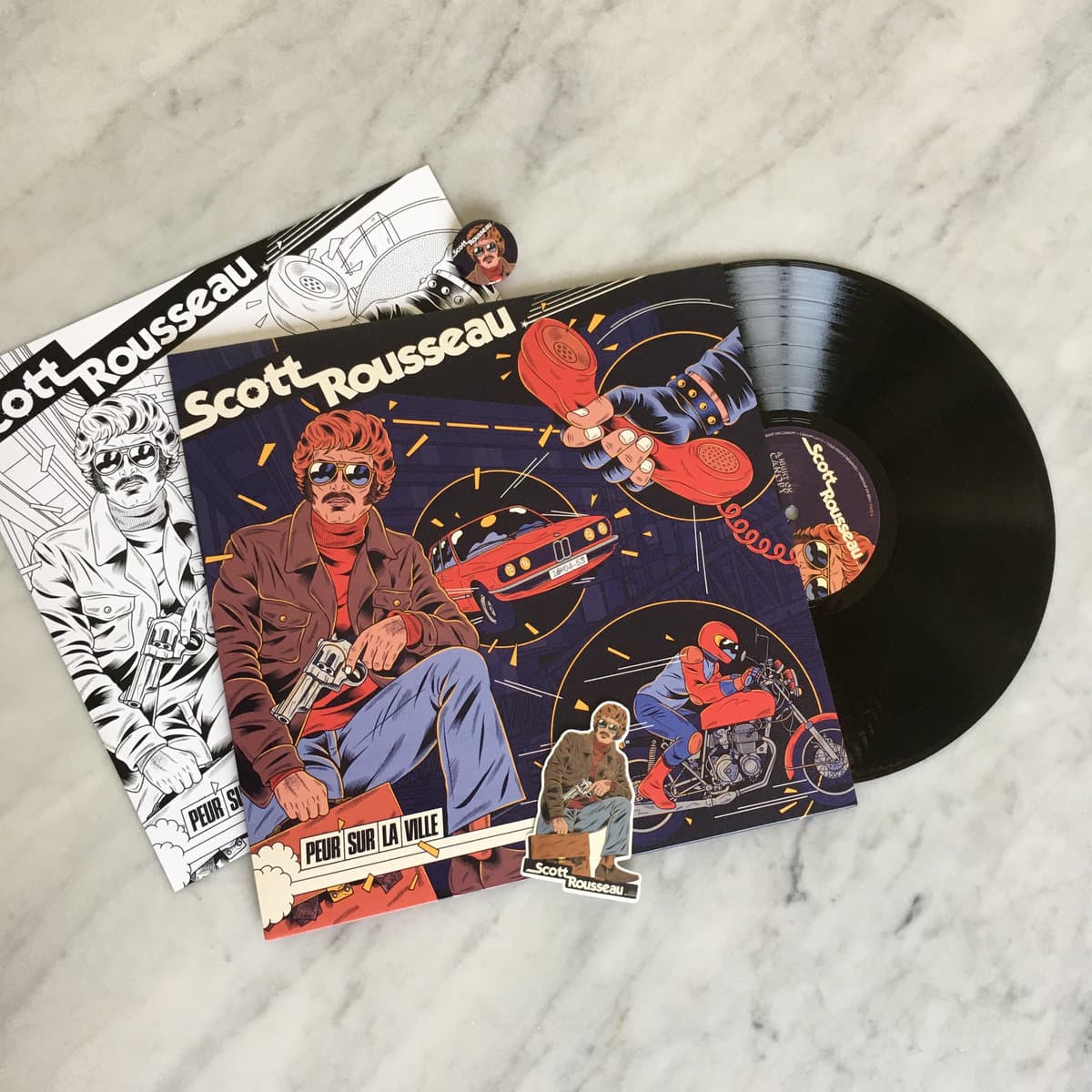 Vinyl record with colorful cover featuring a person on a motorcycle and text, on a marble surface.