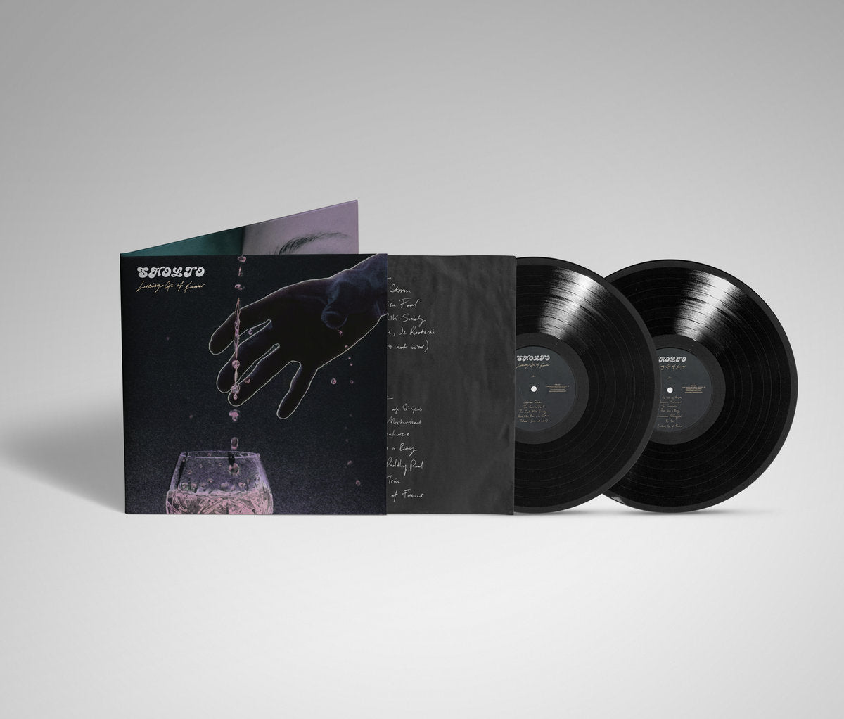 Vinyl record set with a black cover featuring an artistic design on a gray background
